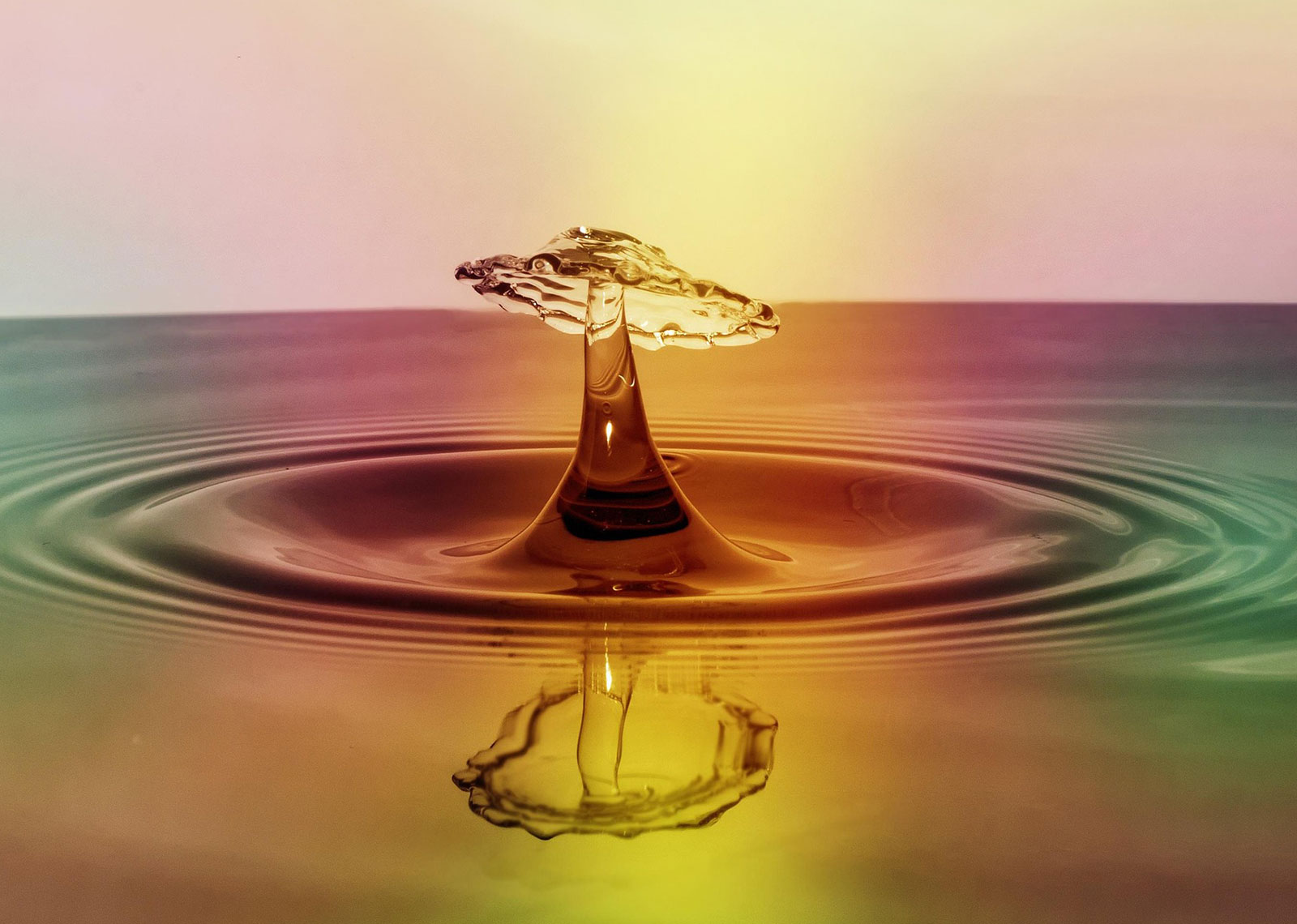 A colorful image of a drop of water landing in a body of water creating ripples to represent how customer experience improvements create ripples even with small inputs.