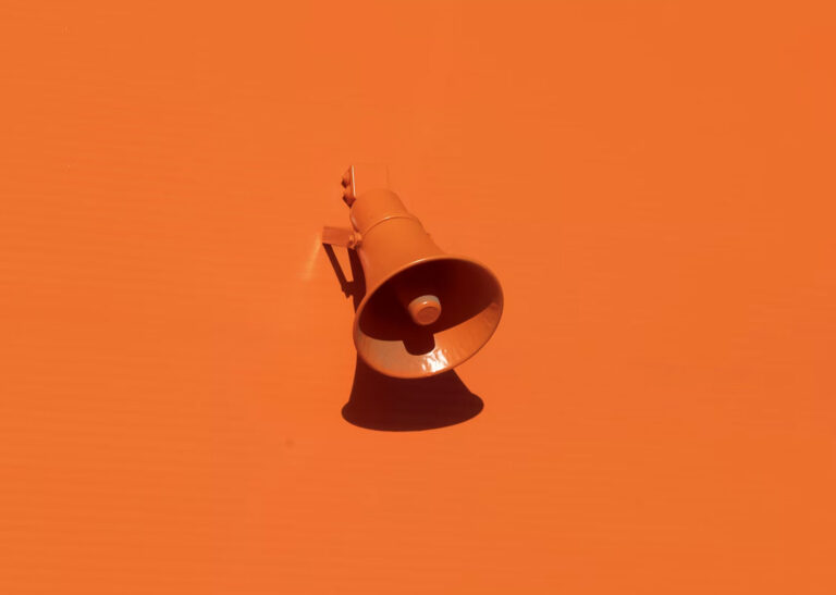 A stark image of a bold orange background with a single orange bullhorn in the center to highlight that being memorable is about more than being everwhere.