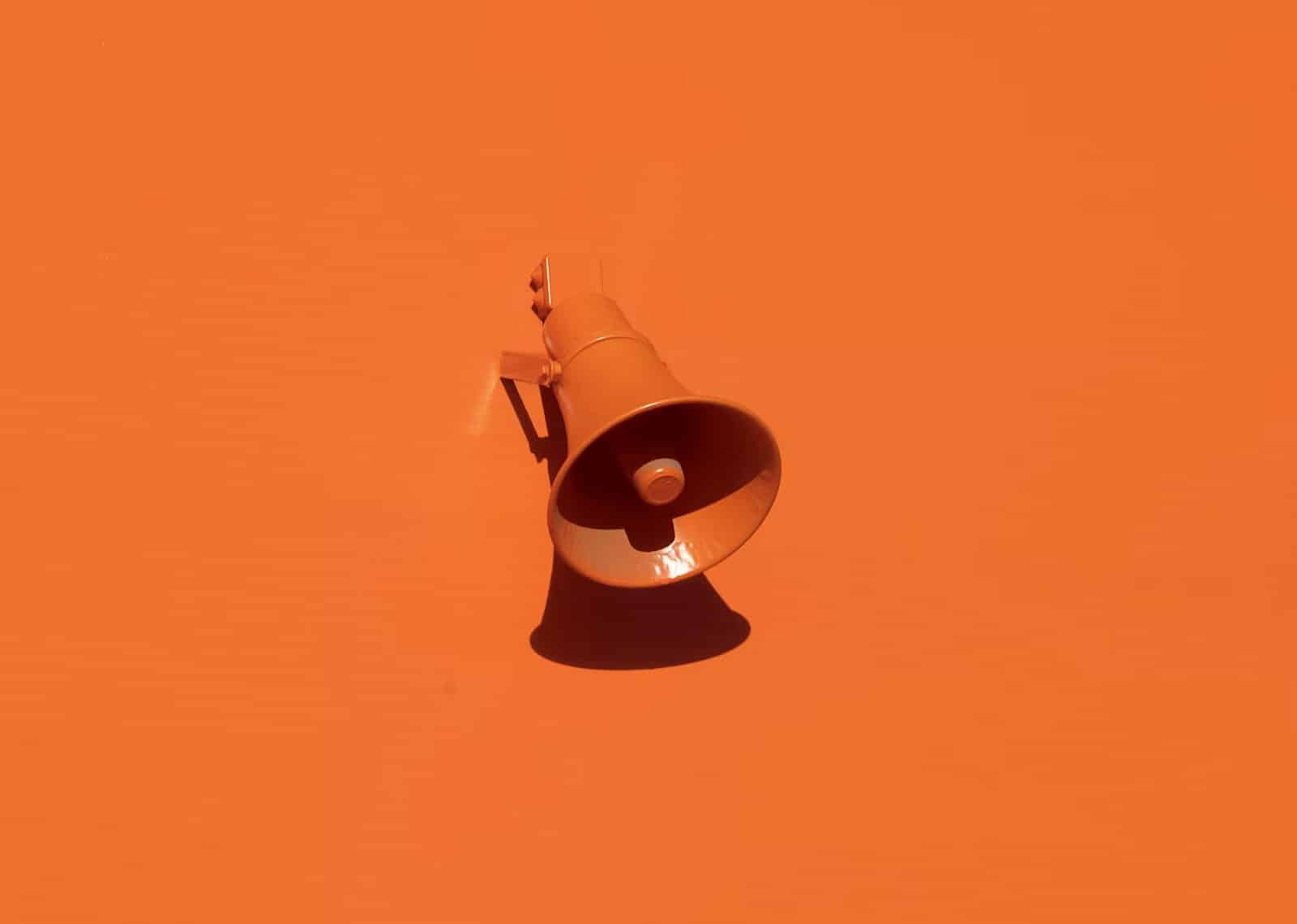 A stark image of a bold orange background with a single orange bullhorn in the center to highlight that being memorable is about more than being everwhere.
