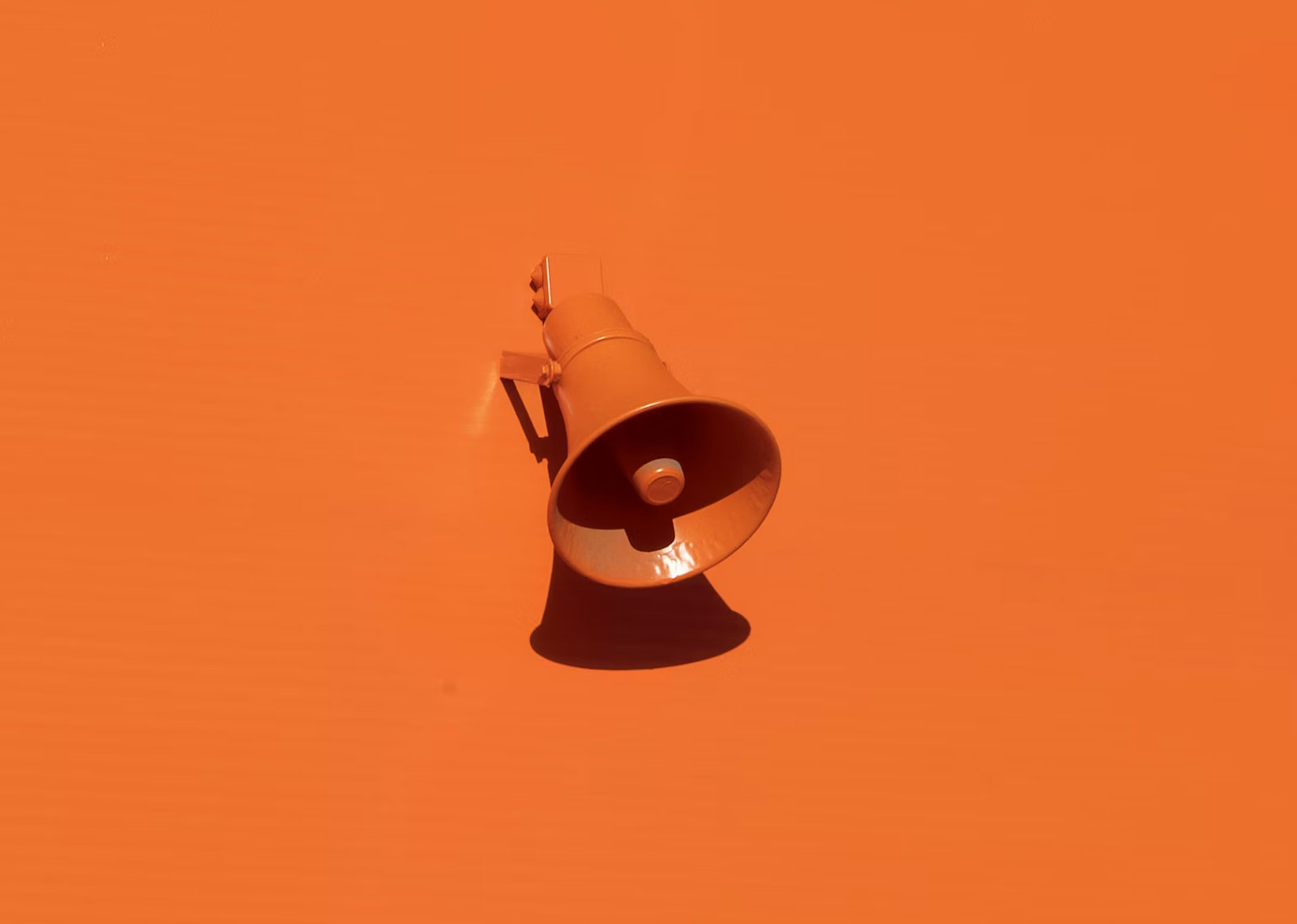 A stark image of a bold orange background with a single orange bullhorn in the center to highlight that being memorable is about more than being everwhere.
